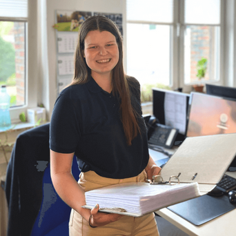 o.t.n Azubi Vivien Waymann mit einem Aktenordner an ihrem Schreibtisch in der Zentrale