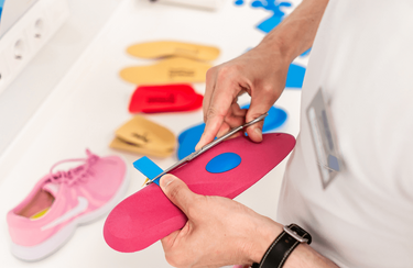 Ein Fachmann für Schuhtechnik schneidet eine bunte Einlage zurecht - Maßfertigung gibt es auch bei o.t.n