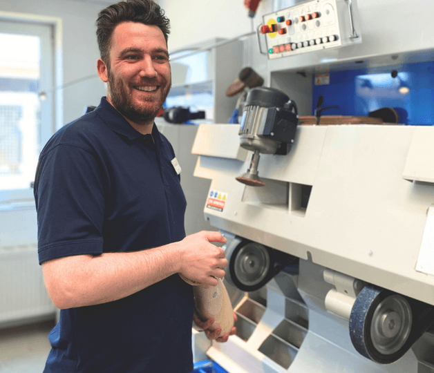 o.t.n Mitarbeiter Thies Goos bearbeitet eine Beinprothese an einer Maschine in der Orthopädiewerkstatt